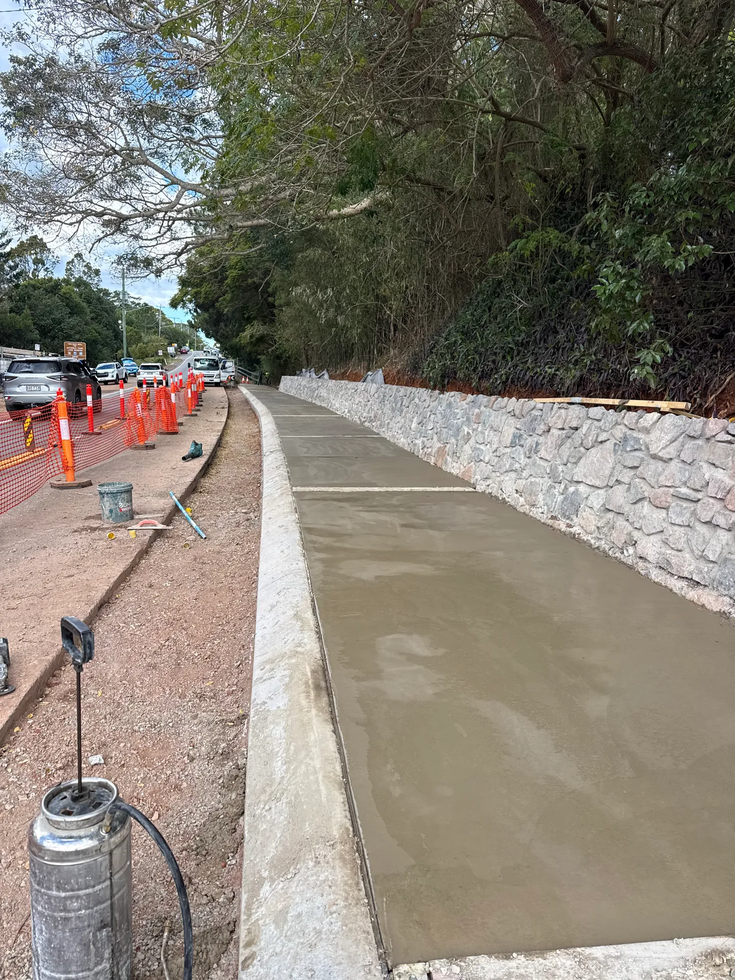 Concrete footpath beside a stone retaining wall completed by JRM Concreting
